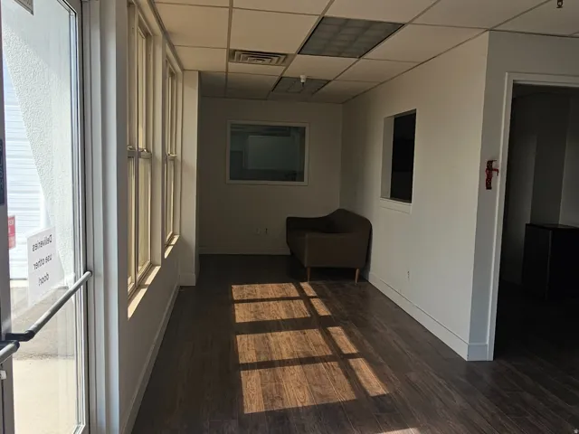 Entryway featuring full-light glass doors, wood-finish flooring, a suspended acoustic ceiling with integrated lighting, and multiple windows along one wall