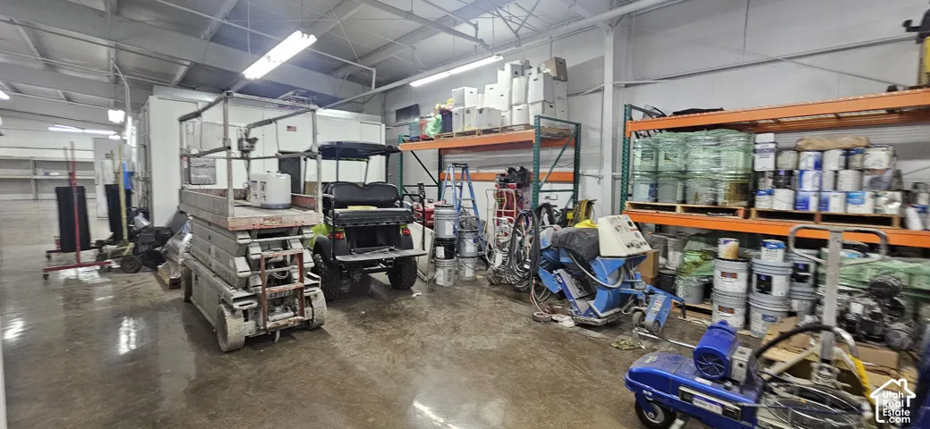 Spacious interior featuring a concrete floor, high ceilings, exposed metal beams, and fluorescent lighting