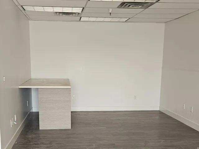 Spacious interior featuring wood-finish flooring, white walls, and a built-in desk with a light-toned countertop