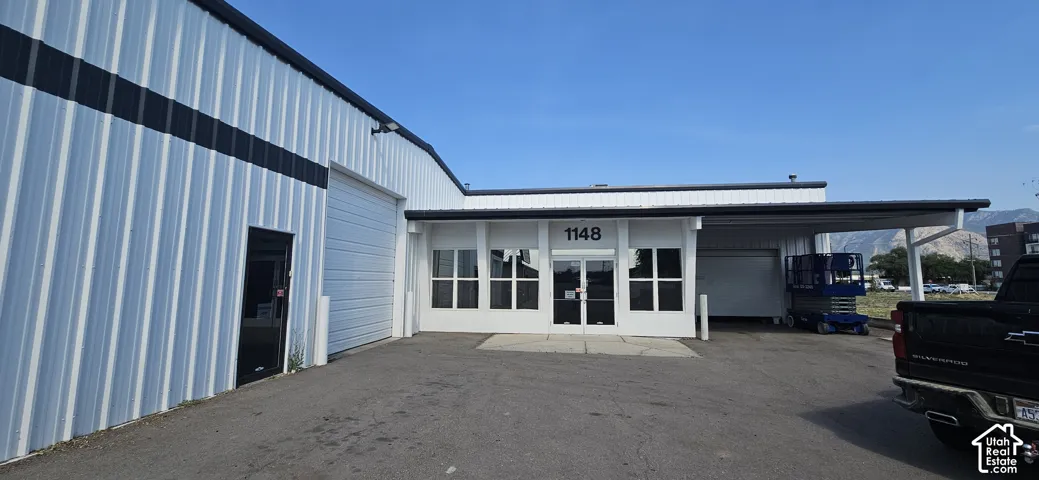 Commercial building featuring a white corrugated metal exterior with black trim, multiple entry points, and a covered loading area
