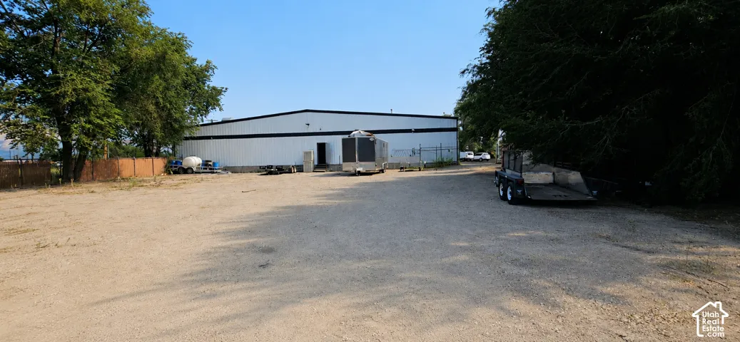 Spacious gravel parking lot fronting a large industrial building with a white metal exterior and black trim