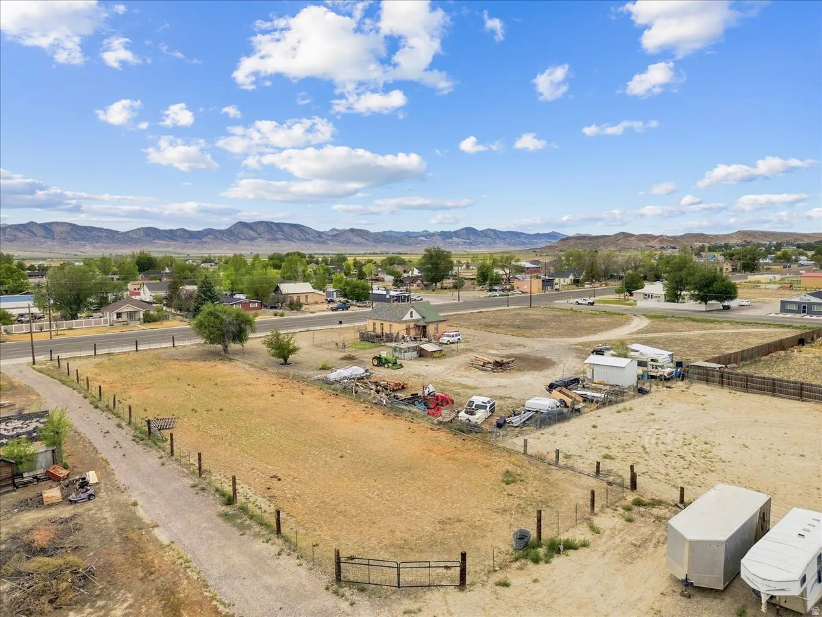 Expansive land parcel featuring a metal gate, perimeter fencing, and established trees