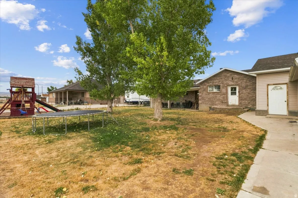Extensive backyard area featuring a brick exterior structure and a separate entrance with vinyl siding