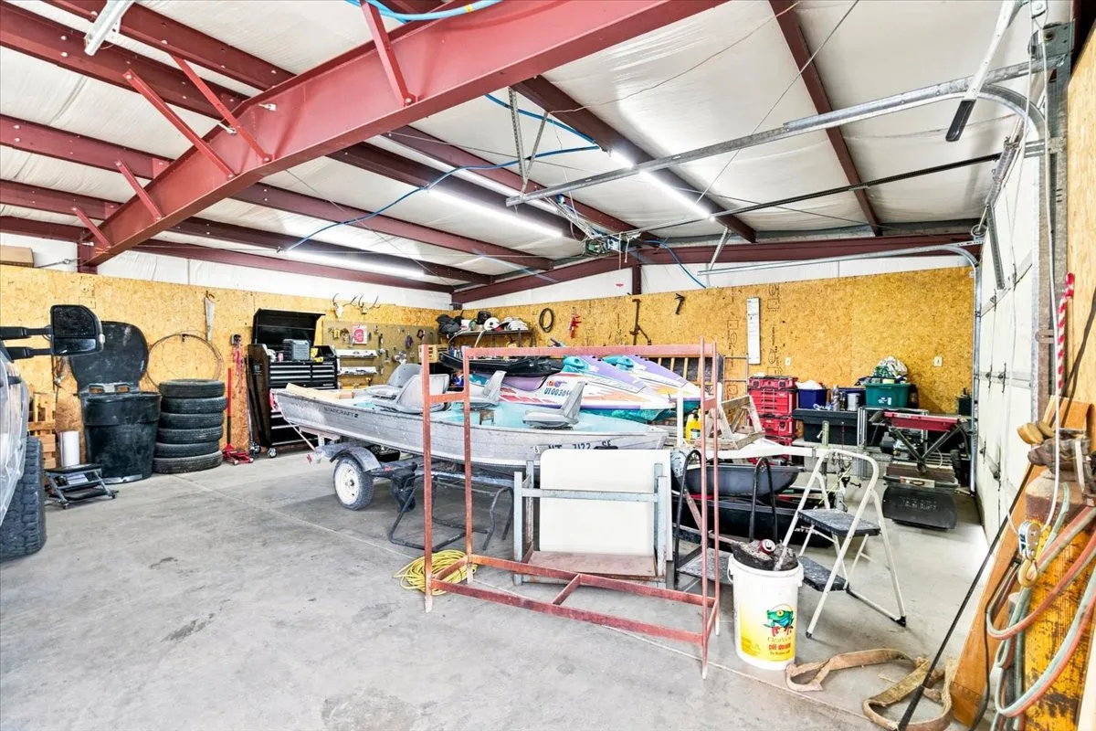 Spacious garage featuring a concrete floor, exposed steel beam construction, overhead lighting, and a large roll-up door