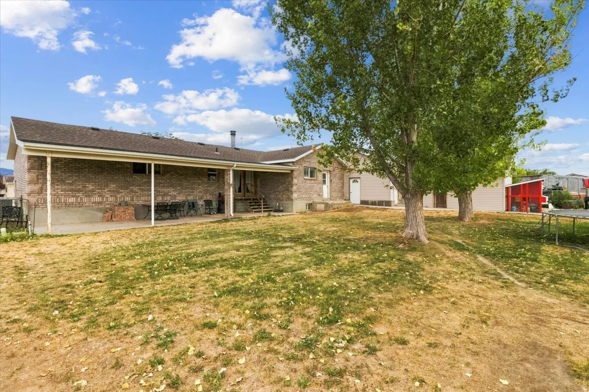 Expansive backyard featuring mature trees and a substantial covered patio area
