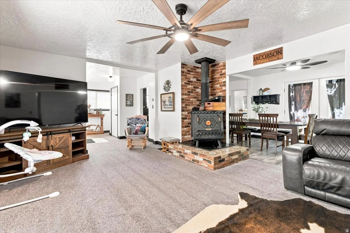 Living area featuring a brick-surround wood stove, recessed lighting, and a large ceiling fan