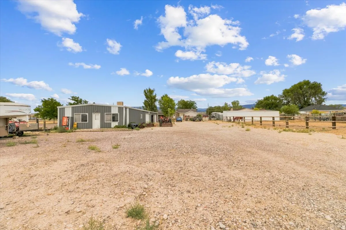 Spacious lot featuring a metal-sided building with multiple windows and a white entry door