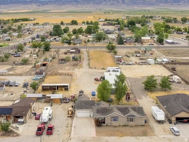 Expansive aerial view of the surrounding area featuring distant mountains, a mix of residential structures, and paved roadways