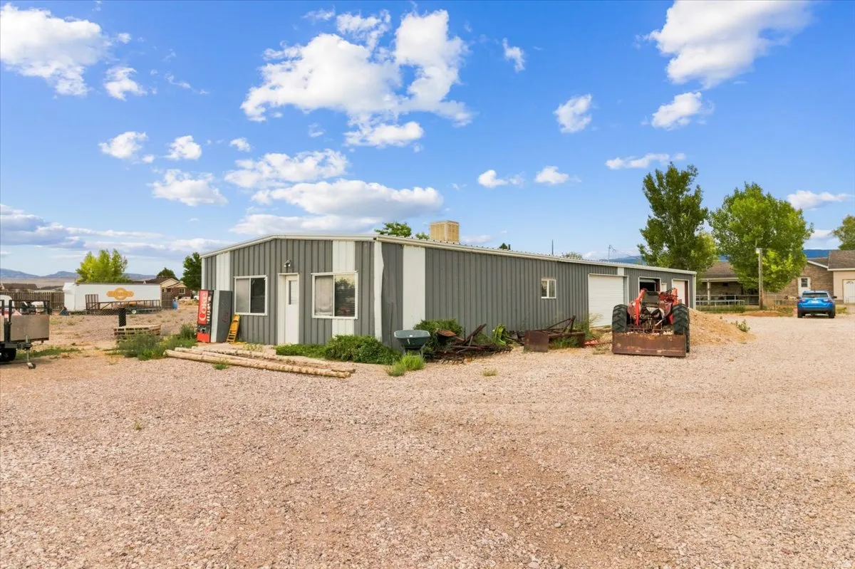 Metal-sided structure featuring multiple entry points and a gravel lot