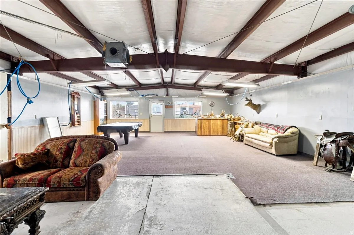 Spacious interior featuring exposed metal beams, overhead lighting, and concrete flooring transitioning to carpet