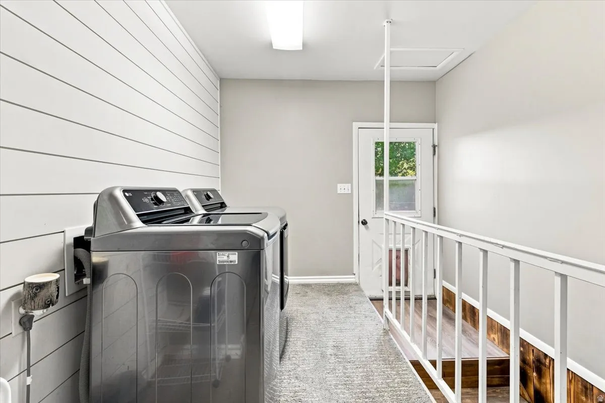 Dedicated laundry area featuring shiplap wall paneling, a neutral wall color, and a textured area rug