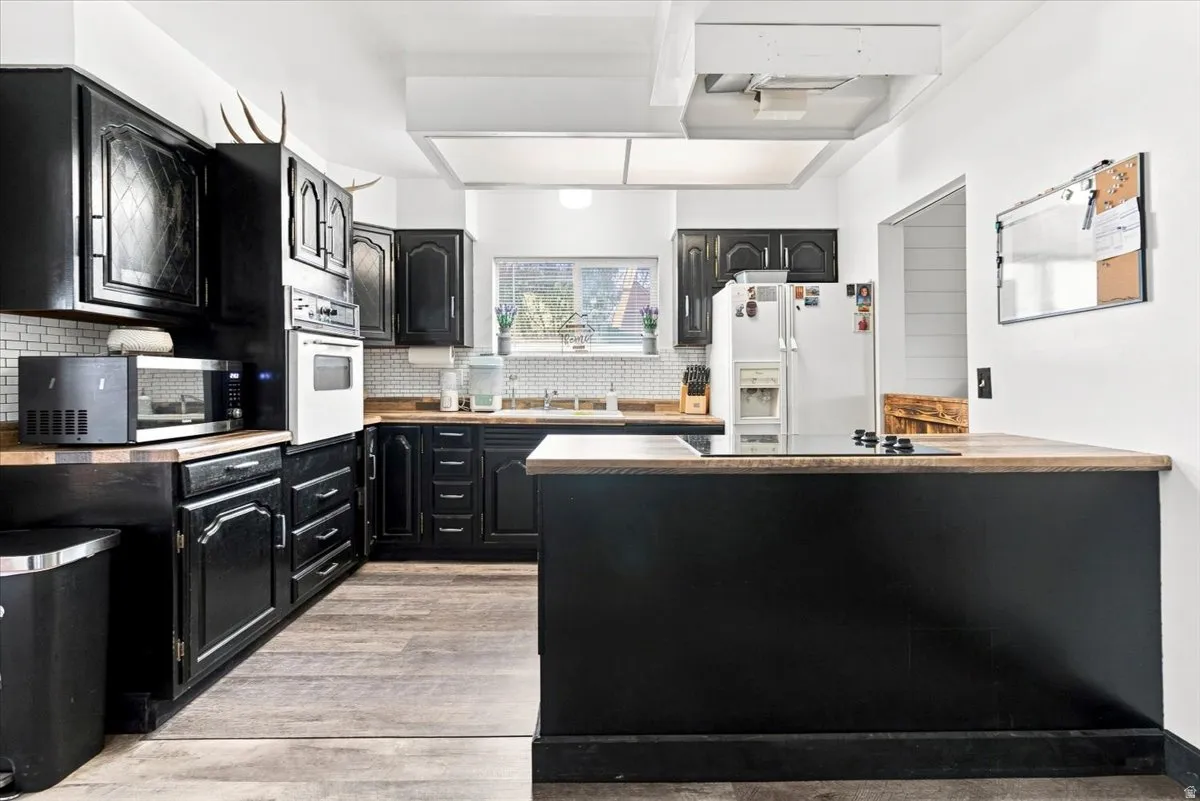 Kitchen featuring dark cabinetry, wood-finish countertops, and a white subway tile backsplash
