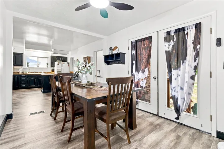 Open-concept dining area featuring wood-finish flooring, a ceiling fan, and French doors
