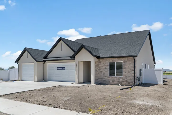 Modern stucco exterior with stone veneer accents, a dark shingle roof, and an attached two-car garage