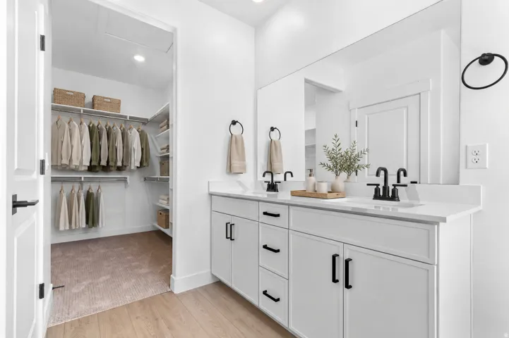 Dual vanity with white cabinetry, matte black fixtures, and a large mirror