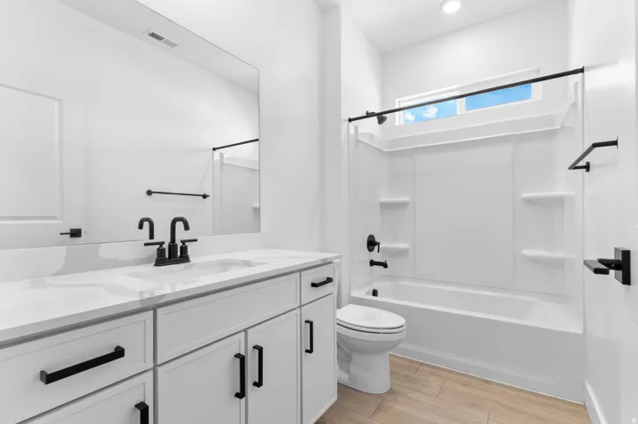 Bathroom featuring a white vanity with a light-toned countertop, a rectangular undermount sink, and matte black fixtures