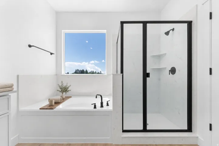 Soaking tub with black-finish fixtures, white tile surround, and a large window
