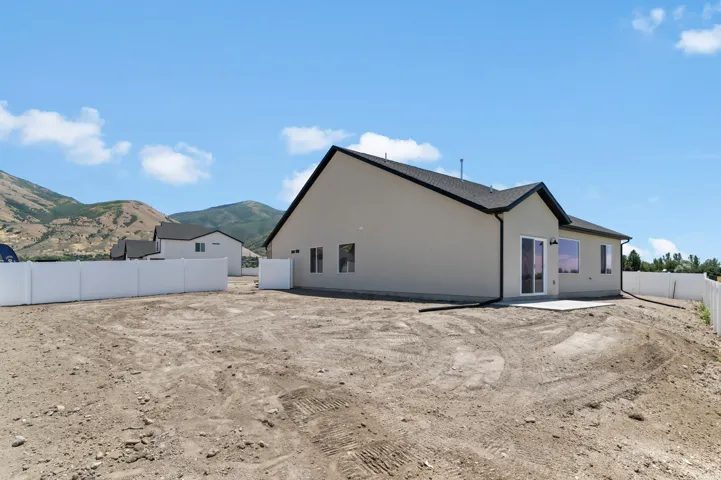 Spacious backyard offering ample room for customization, featuring a concrete patio, sliding glass door, and a white privacy fence