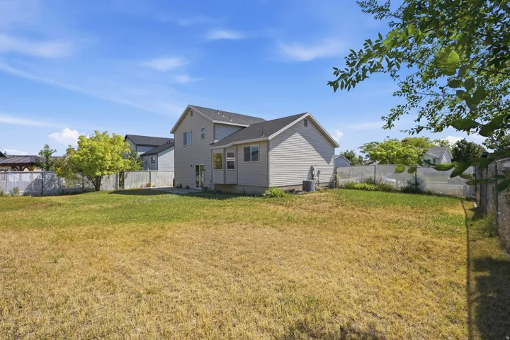 Expansive backyard featuring a concrete patio, mature tree, and partial fencing