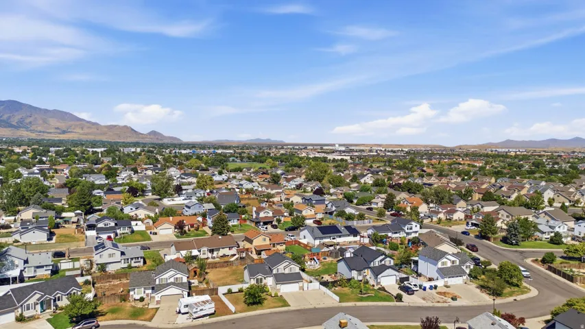 Expansive residential area featuring numerous single-family homes, mature trees, and mountainous terrain in the distance