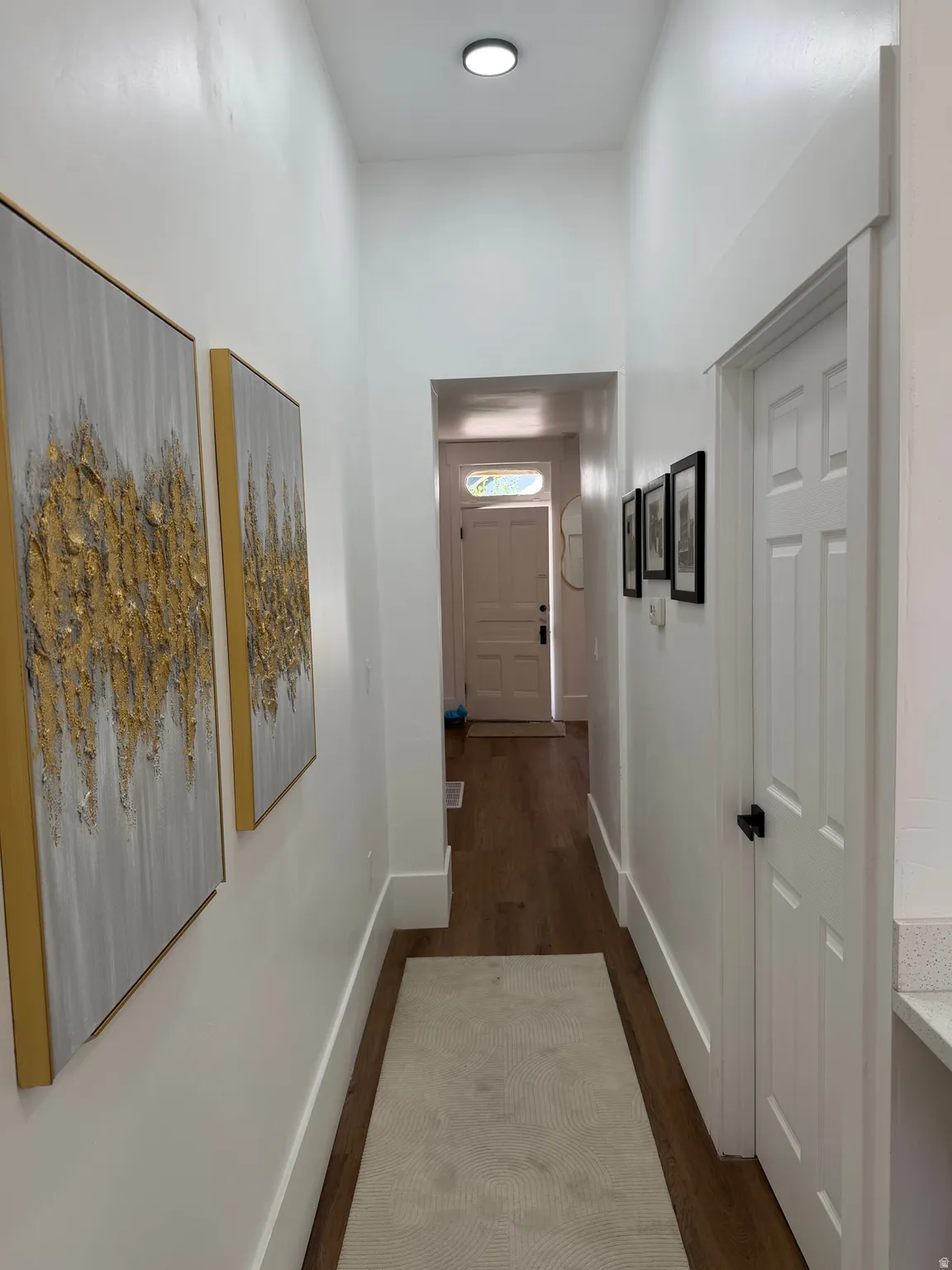 Hallway featuring wood-finish flooring, recessed lighting, and crisp white trim