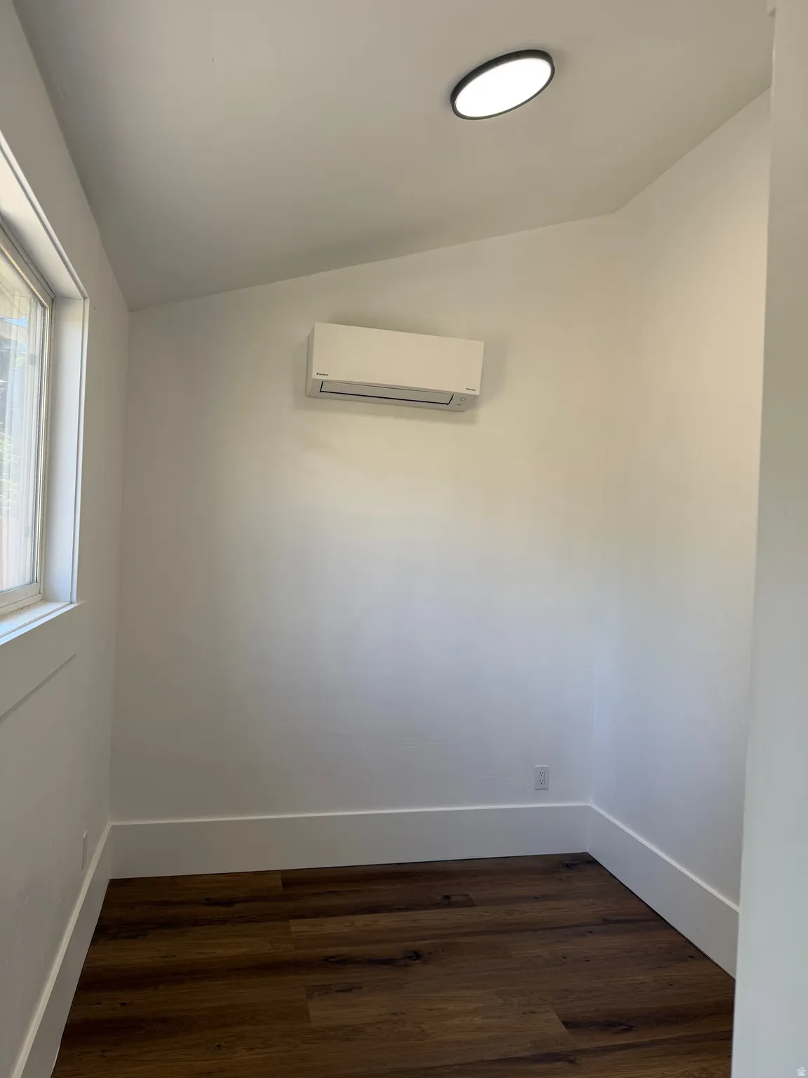 Compact room featuring wood-finish flooring and a contemporary recessed ceiling light