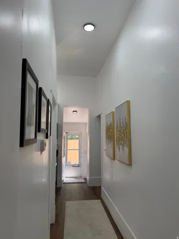 Hardwood-style flooring extends through a bright hallway with recessed lighting