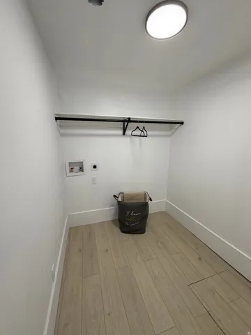Dedicated utility area featuring wood-finish flooring and a flush-mount ceiling light