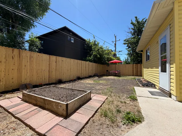 Private backyard space featuring a new wood fence, a raised garden bed with paver surround, and a concrete patio