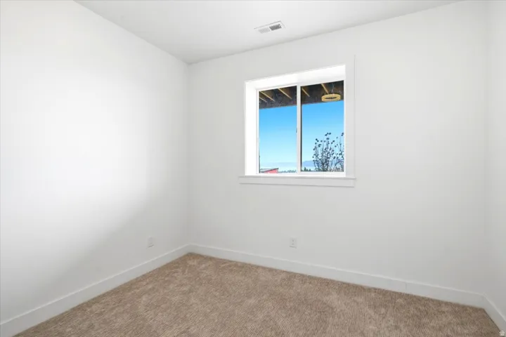 Neutral wall finishes with a single window, white trim, and light brown carpeting
