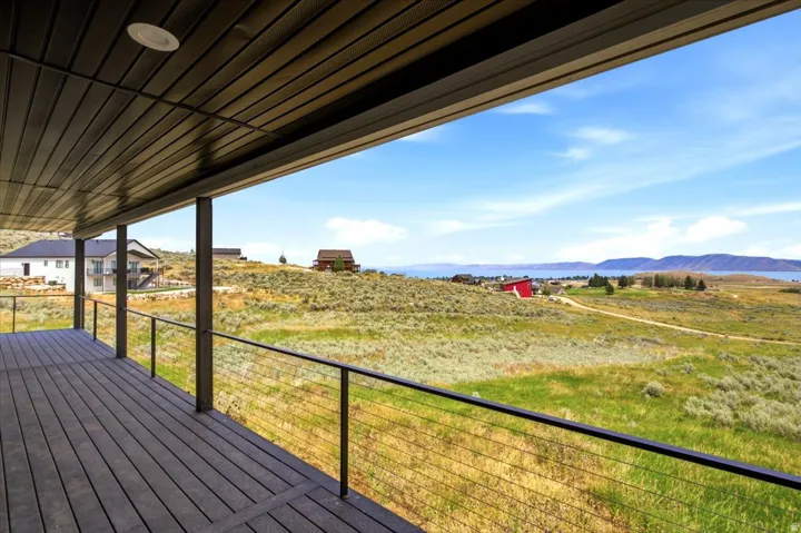 Covered outdoor deck featuring composite decking, cable railing, and recessed lighting