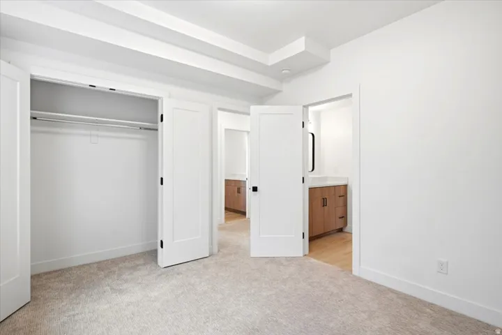 Bright bedroom featuring light carpet flooring and a tray ceiling