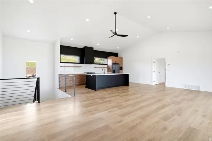 Expansive open-concept living space featuring vaulted ceilings, recessed lighting, and wood-finish flooring