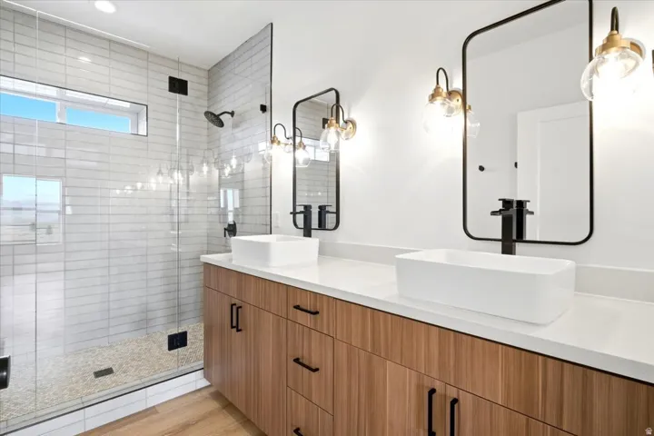Dual vanity featuring wood-finish cabinetry, white countertops, and rectangular vessel sinks with matte black faucets