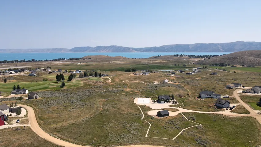 Expansive aerial view showcasing a large body of water, distant hills, and scattered residences