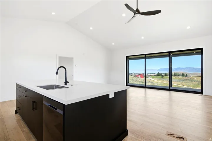 Open-concept living space featuring a vaulted ceiling with recessed lighting, a modern ceiling fan, and light wood-finish flooring