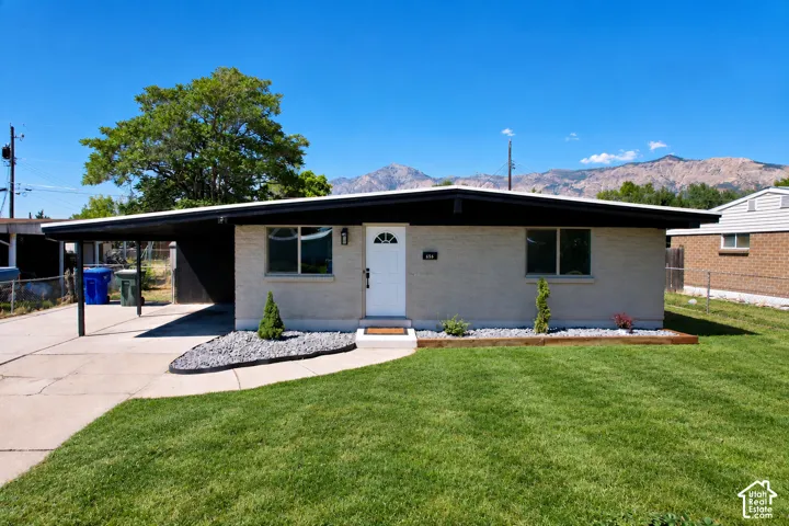 Single-story residence featuring a brick facade, attached carport, low-pitch roof, and mountain scenery