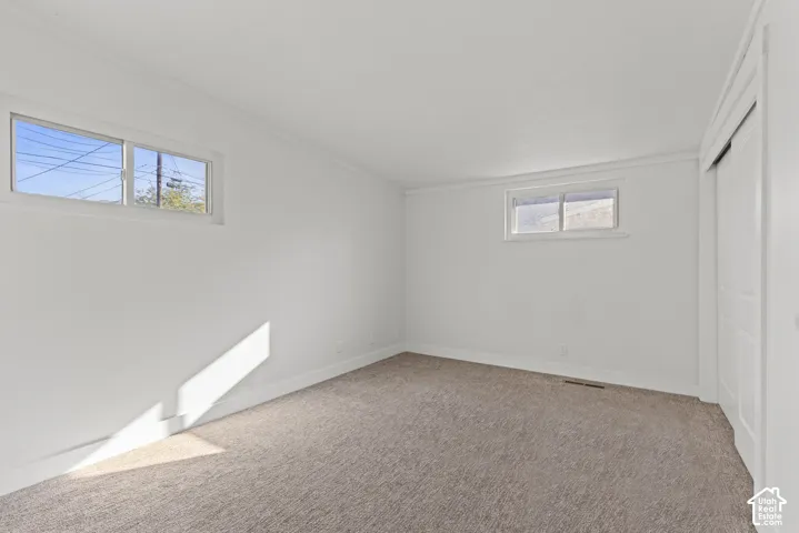 Neutral-toned wall-to-wall carpeting, dual sliding-window installations, and white interior door with raised-panel detailing