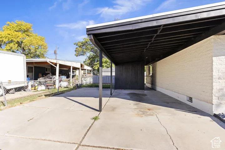 Covered carport featuring a concrete pad and painted wood siding exterior