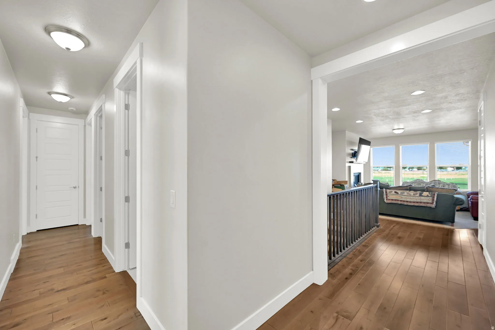 Hallway featuring wood-finish flooring, white paneled doors, and flush-mount ceiling lighting
