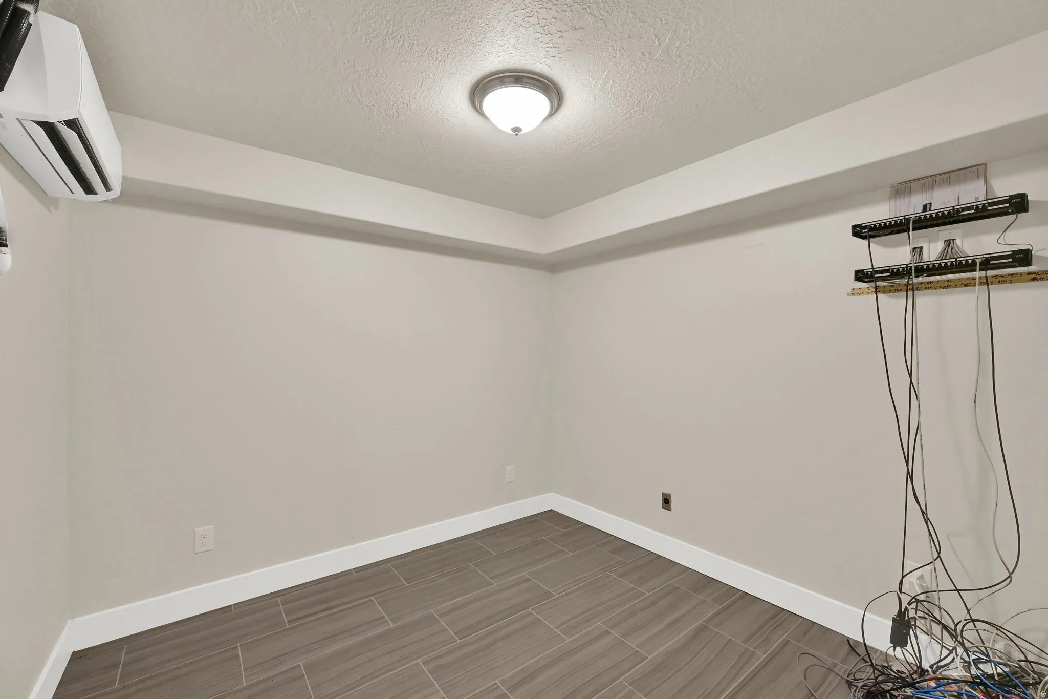 Room featuring wood-look tile flooring, neutral wall paint, white baseboards, and a flush-mount ceiling light