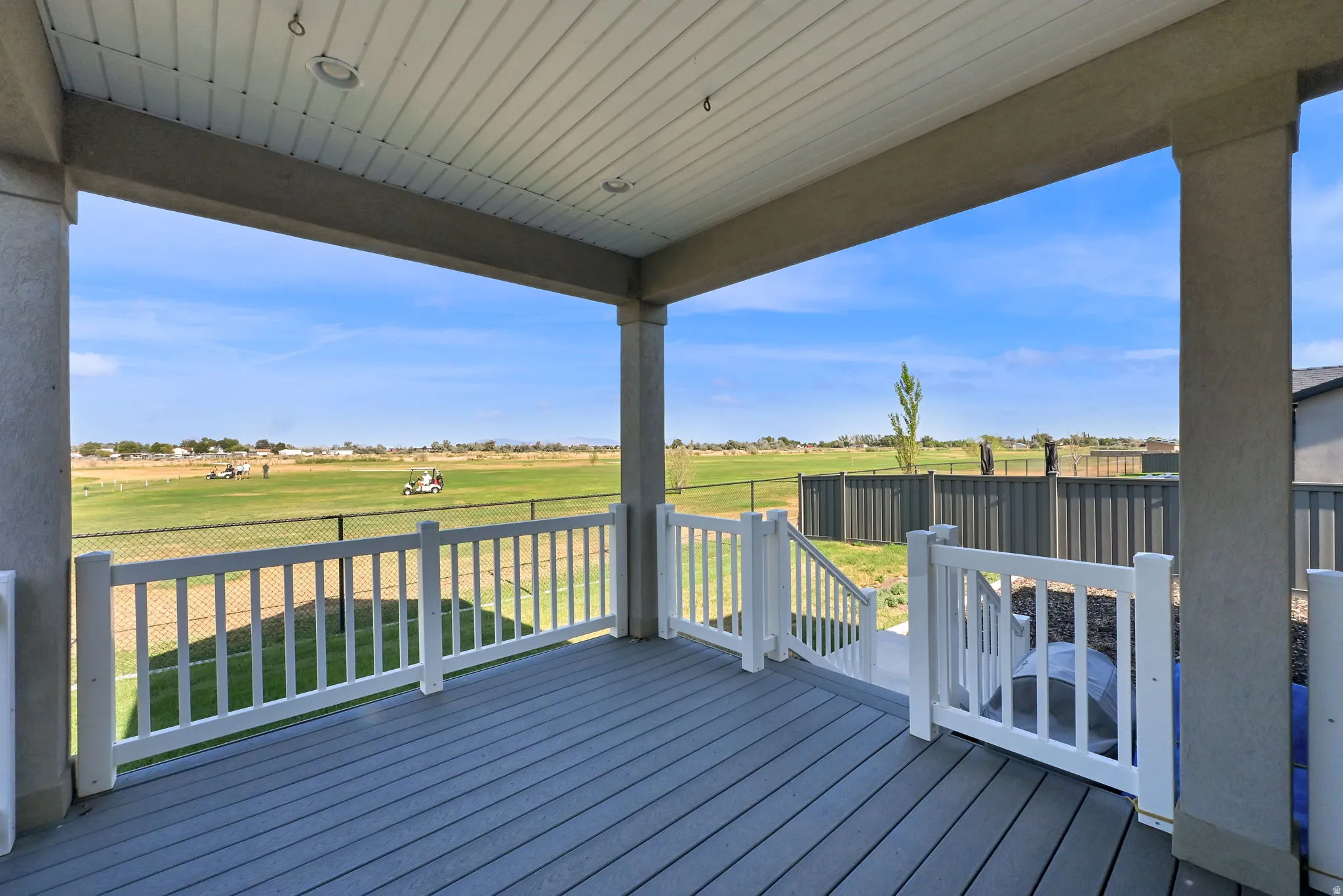 Covered patio with composite decking and white railing overlooking a golf course