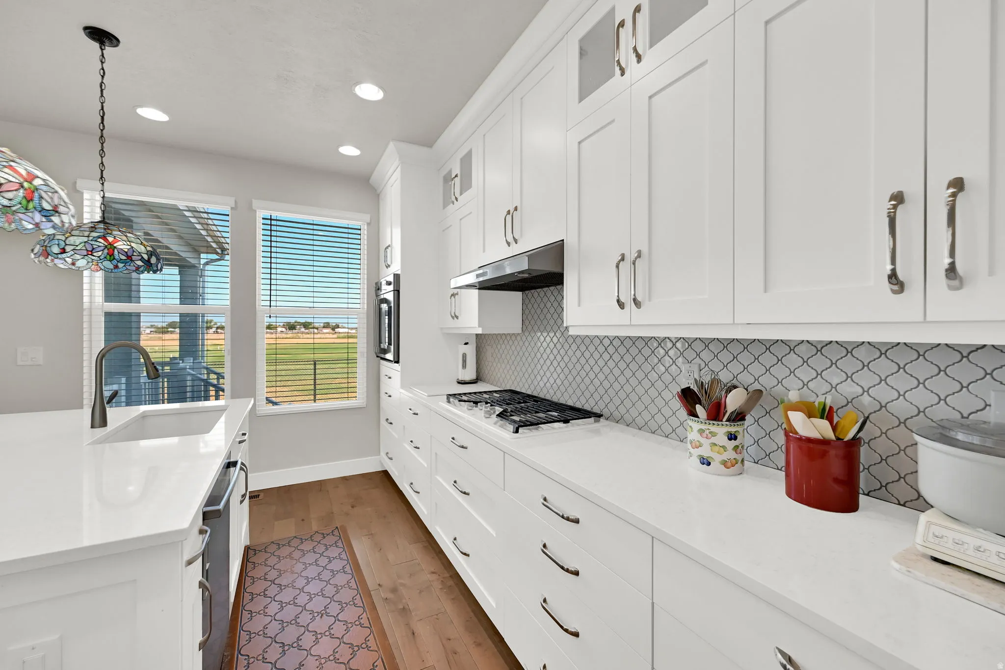Modern kitchen featuring white shaker cabinetry, light-toned countertops, and a decorative backsplash