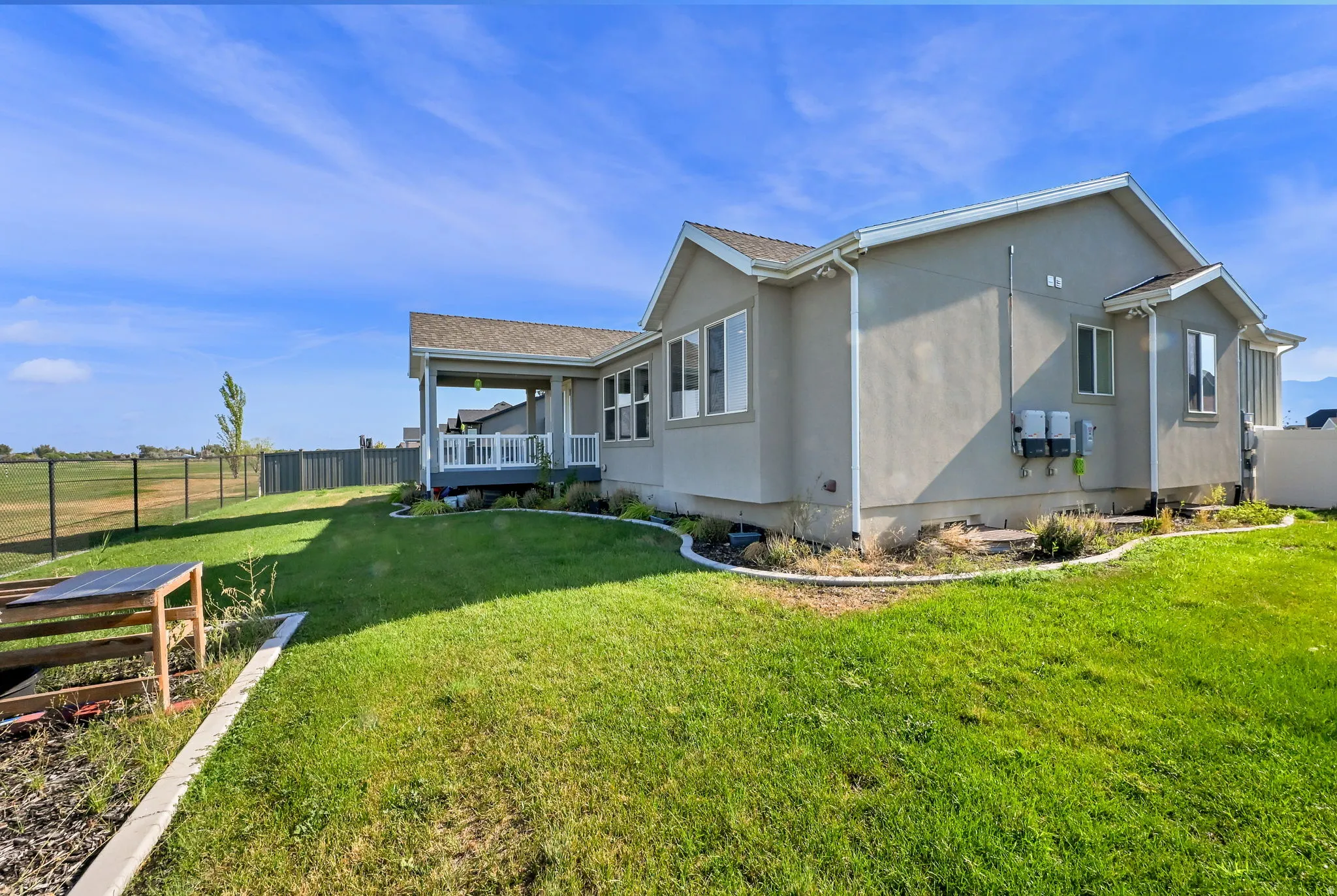 Expansive green lawn surrounds a stucco-exterior residence