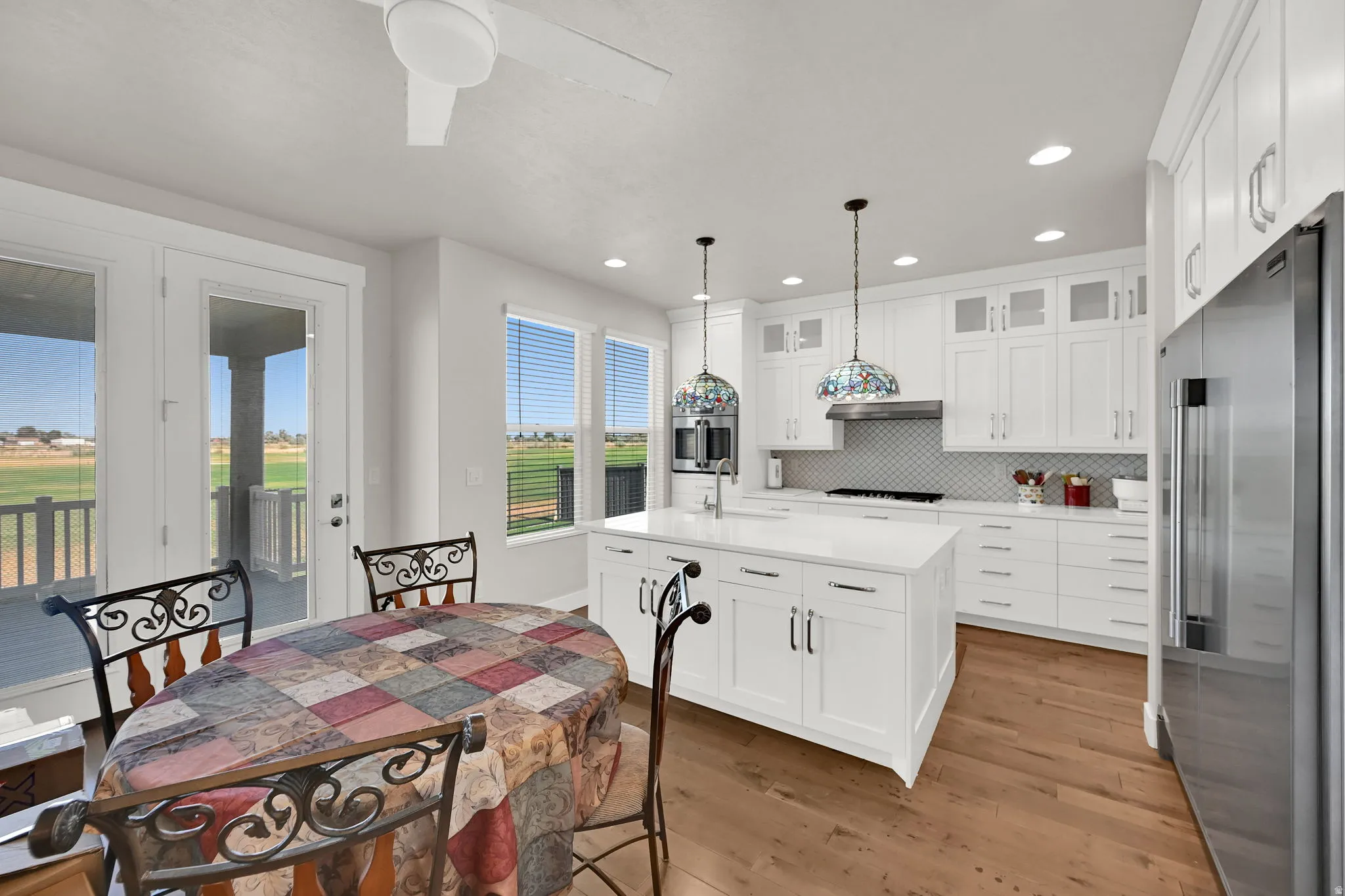 Contemporary kitchen featuring white cabinetry, a center island with pendant lighting, stainless steel appliances, and wood-finish flooring