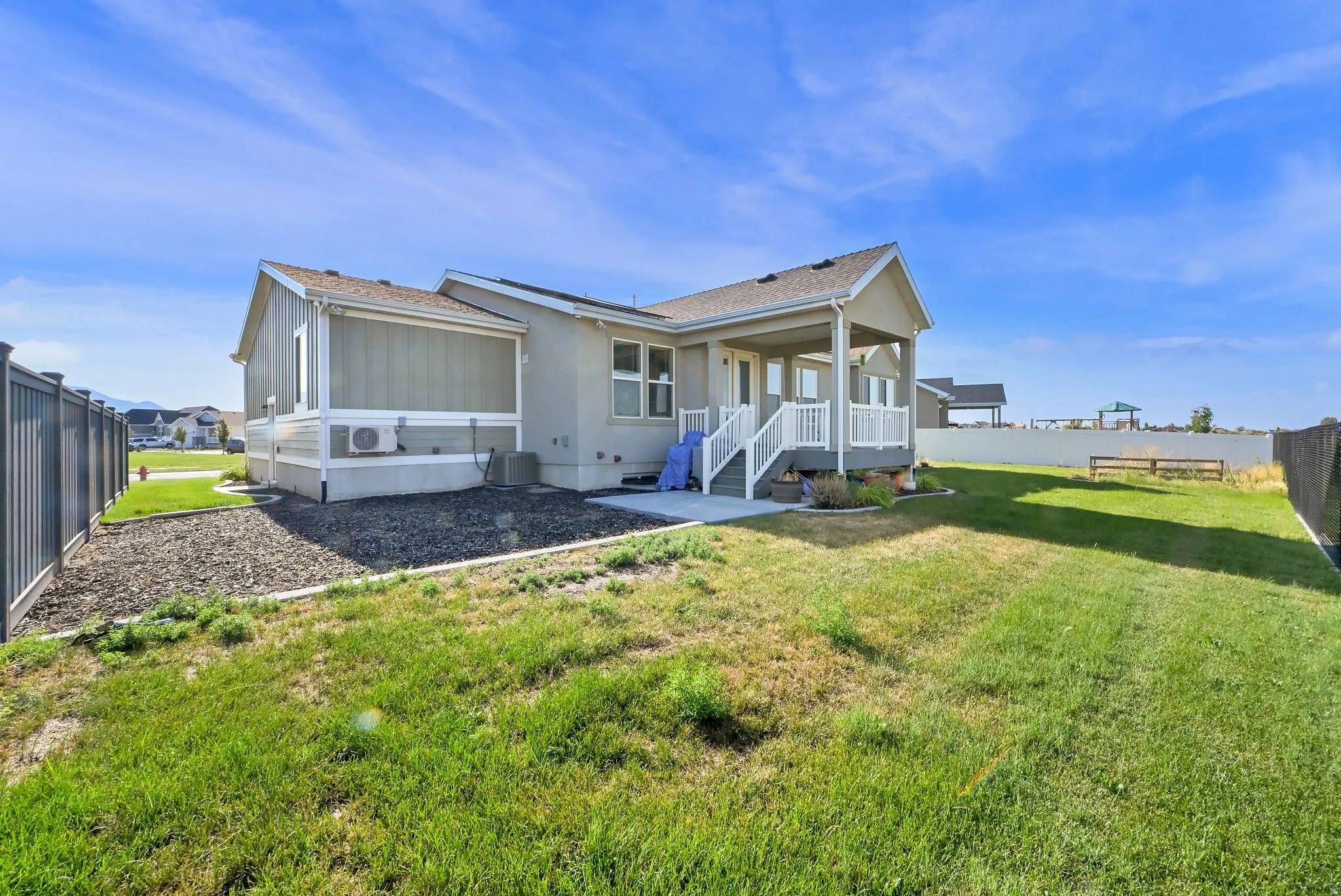 Expansive backyard featuring a covered patio, concrete pad, privacy fencing, and gravel landscaping