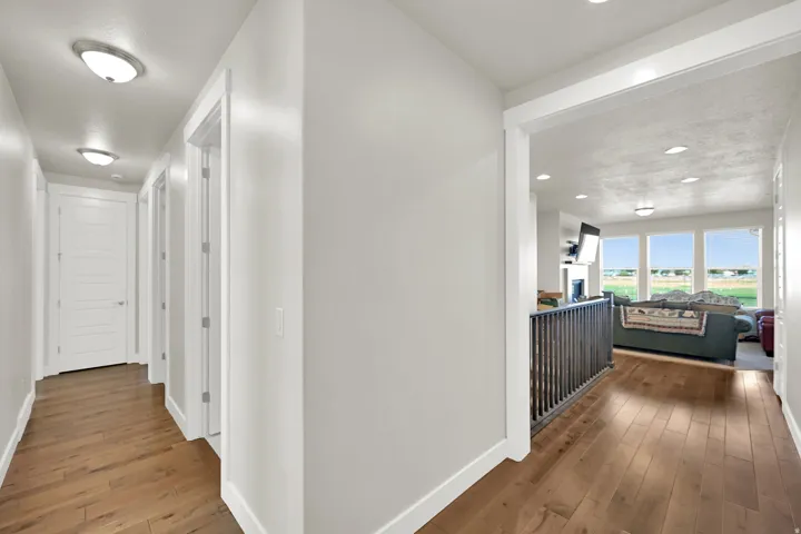 Hallway featuring wood-finish flooring, white paneled doors, and flush-mount ceiling lighting