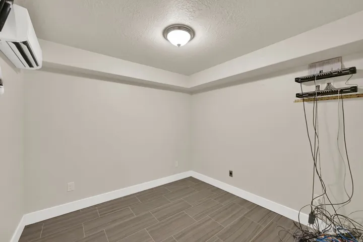 Room featuring wood-look tile flooring, neutral wall paint, white baseboards, and a flush-mount ceiling light