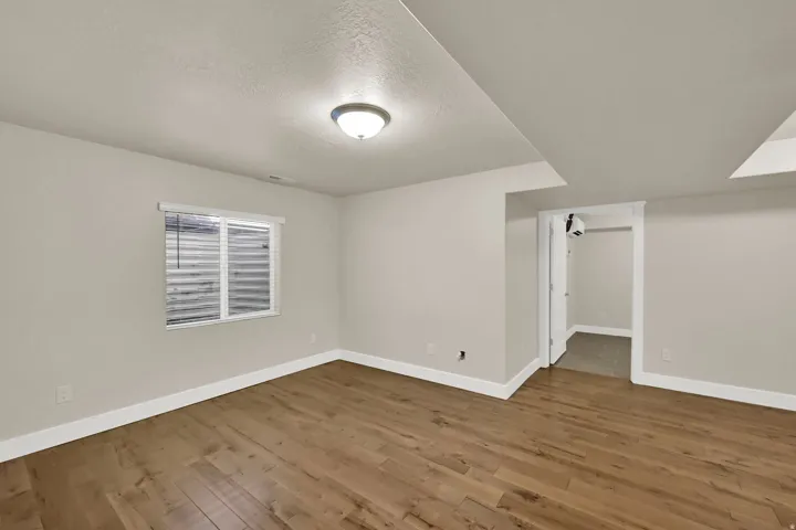 Spacious room featuring wood-finish flooring, light neutral wall paint, and white trim