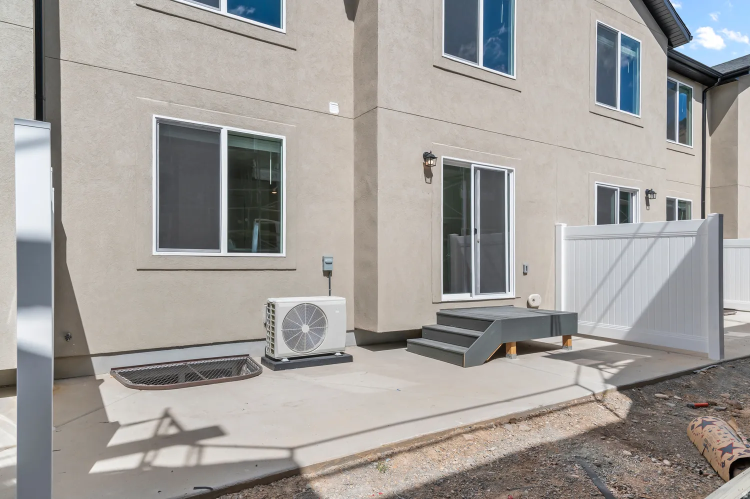 Rear exterior featuring a sliding glass door, modern outdoor lighting, a privacy fence, and an outdoor HVAC unit